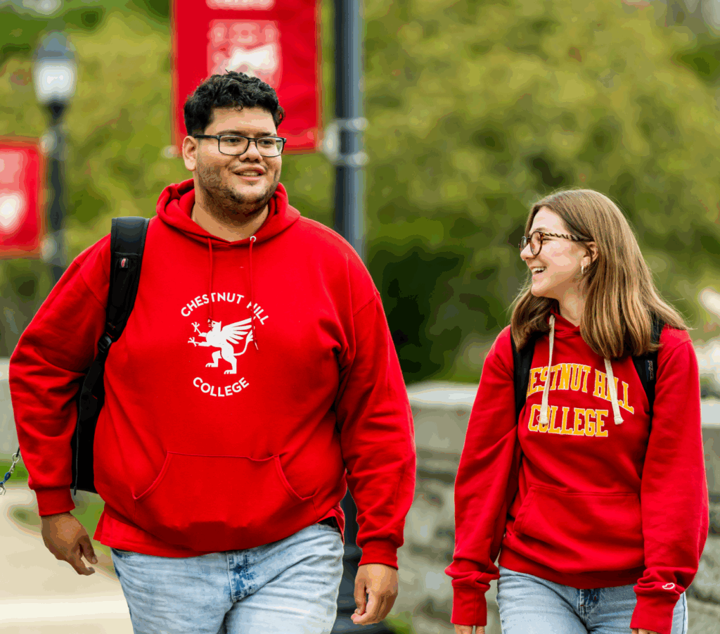 2 students walking on campus in chestnut hill college gear